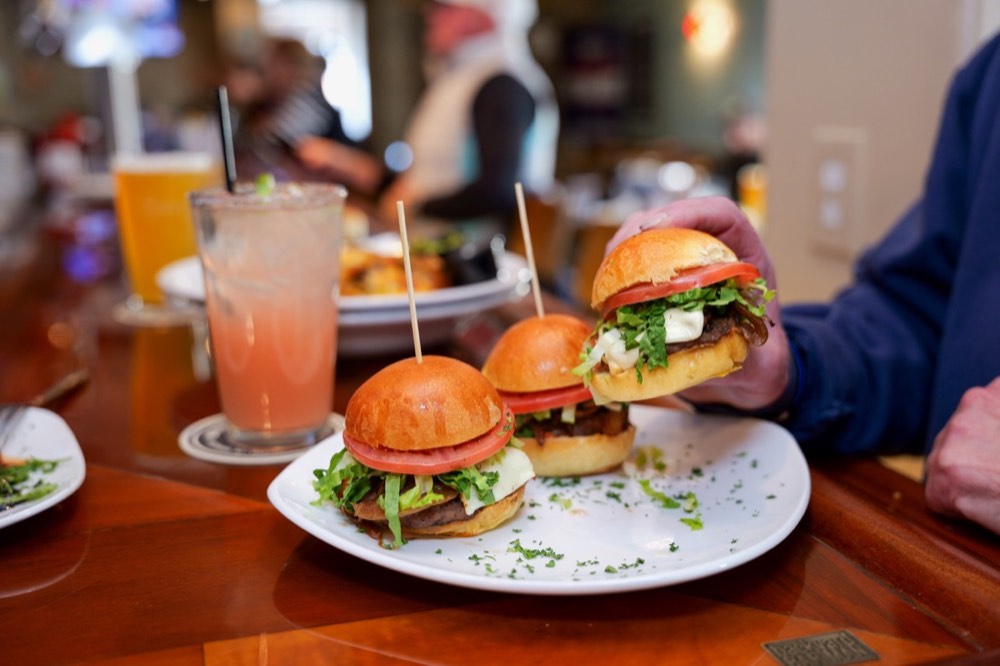 Trio of sliders with arugula on a plate at Dogtooth Bar and Grill