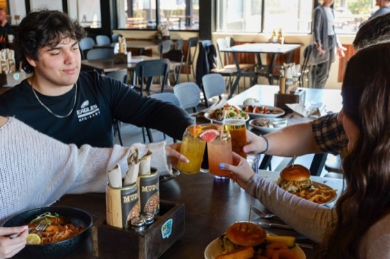 Friends raising a toast across a table in the MudHen taproom