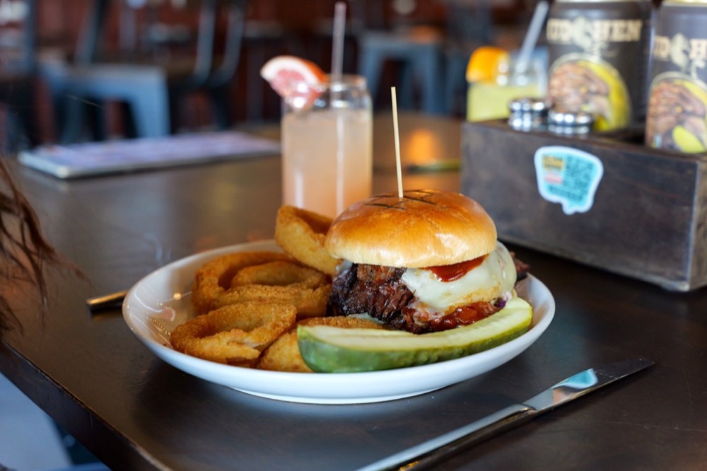 Loaded burger with onion rings and a cocktail at MudHen Brewing