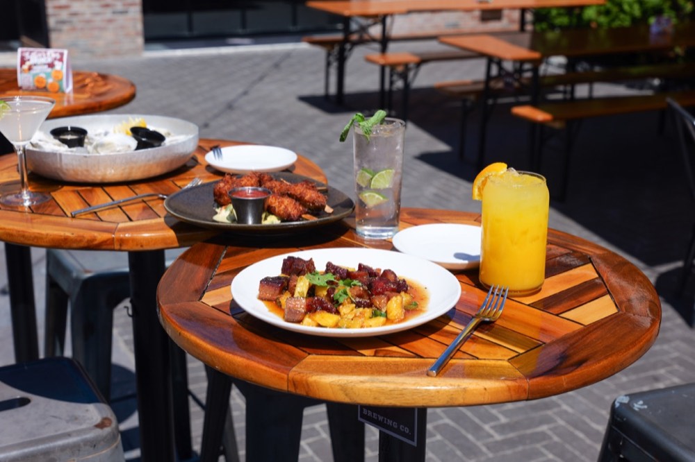 Outdoor biergarten tables set with food and cocktails at MudHen Brewing Company