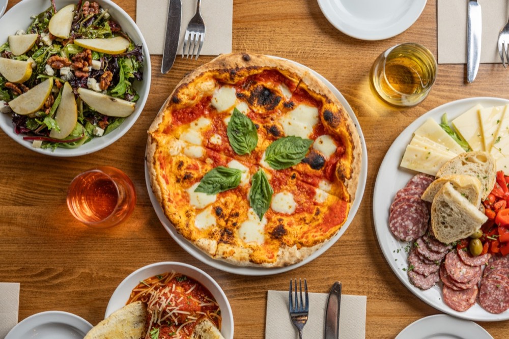 Margherita pizza, charcuterie and pasta laid out on a table at Poppi's Brick Oven