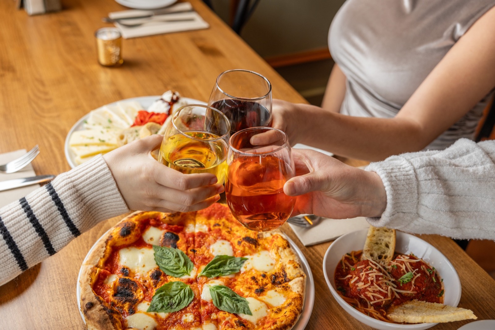 Guests toasting over a fresh brick-oven pizza at Poppi's