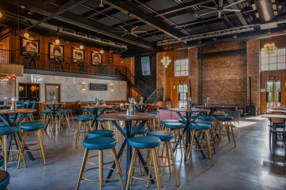 The open brick-and-timber main hall at The Station House set with high-top tables
